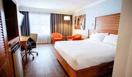 Hotelzimmer mit großem Bett, Schreibtisch und Sitzgelegenheiten im Hôtel Lindbergh auf Kanada-Singlereisen.