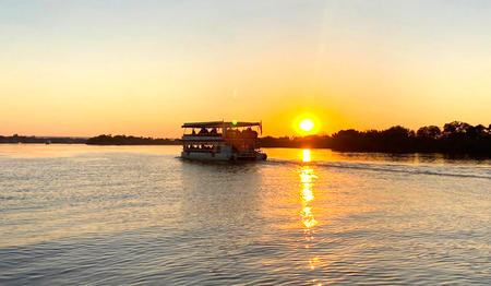 Ausflugsboot auf dem Sambesi im goldenen Abendlicht: Singles & Alleinreisende buchen bei singlereisen.de