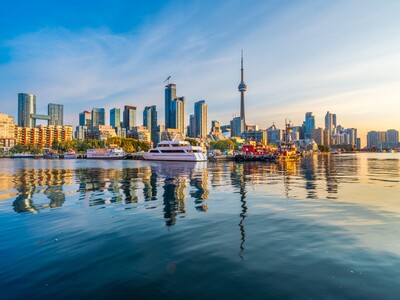 Die berühmte Skyline von Toronto mit dem CN Tower spiegelt sich bei Sonnenuntergang im Wasser des Ontariosees.