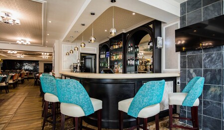 Elegante Hotelbar mit blauen Barhockern: Singles & Alleinreisende buchen bei singlereisen.de