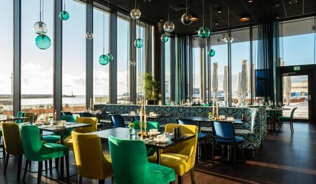 Bunt gedeckte Tische im modernen Restaurant des Hotels mit Blick auf das winterliche Nordnorwegen.