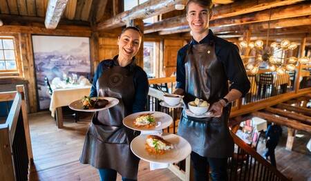 Zwei freundliche Servicemitarbeiter präsentieren traditionelle norwegische Fisch- und Fleischgerichte im Urlaub für Singles.