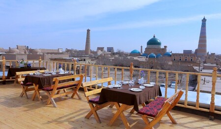 Tische auf der Dachterrasse des Hotels Arkanchi mit Blick auf die Minarette von Chiwa während der Rundreise Usbekistan.
