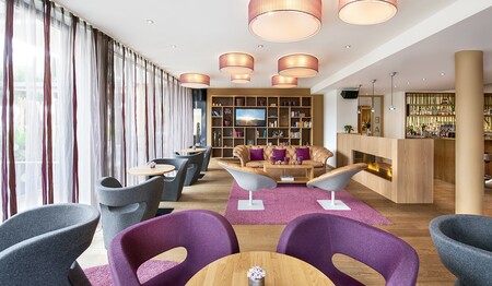Stilvoll eingerichtete Hotelbar und Lounge mit lila Sesseln und gemütlichem Kamin für entspannte Gespräche unter Singles.