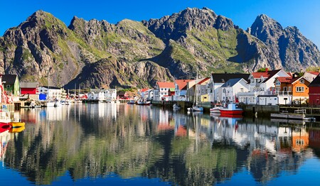 Hafen von Svolvær auf den Lofoten bei klarem Wetter mit bunten Häusern und Bergen für Singlereisen nach Norwegen.