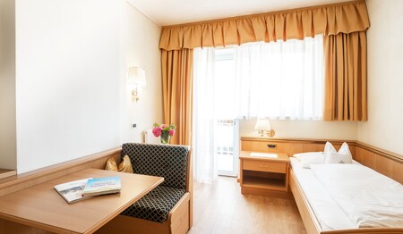 Einzelzimmer im alpinen Design mit Sitzgarnitur im Hotel Adler – ideal für Singlereisende