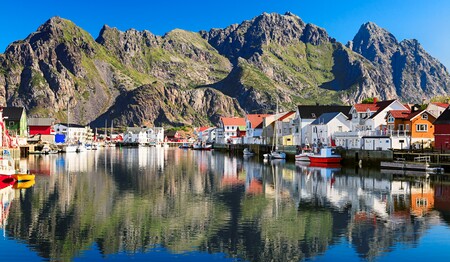 Hafen von Svolvær auf den Lofoten bei klarem Wetter mit bunten Häusern und Bergen für Singlereisen nach Norwegen.