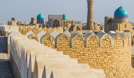 Blick von der historischen Stadtmauer der Zitadelle Ark über die Lehmbauten und blauen Kuppeln der Altstadt von Buchara in Usbekistan auf einer Rundreise.