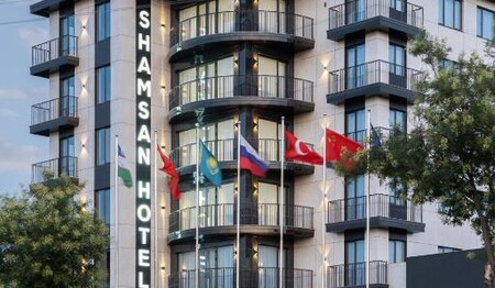 Die mehrstöckige, beleuchtete Fassade des Hotels Shamsan in Taschkent an einer Straße während einer Usbekistan Rundreise.