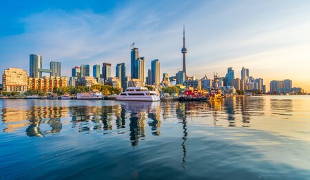 Die berühmte Skyline von Toronto mit dem CN Tower spiegelt sich bei Sonnenuntergang im Wasser des Ontariosees.