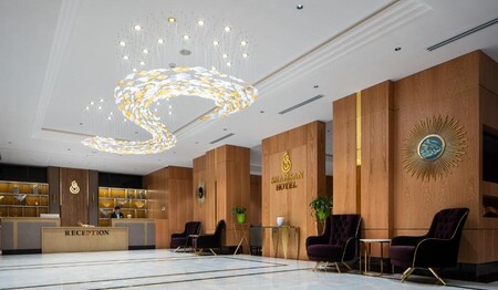 Die luxuriöse Lobby des Hotels Shamsan mit Holzverkleidung, Sesseln und der Rezeption für Singles & Alleinreisende.