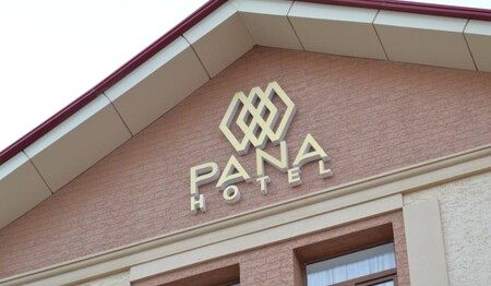 Die gepflegte Außenfassade des Hotels Pana mit dem goldenen Hotellogo unter dem Giebel während einer Singlereise in Usbekistan.
