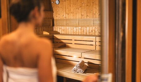 Eine Frau von hinten im gemütlich warmen Saunabereich des Hotels – perfekt zum Regenerieren nach einer Alpentour für Alleinreisende.